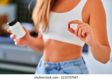 Fit woman taking medicine for supporting slim body at home - Shutterstock ID 2215707047