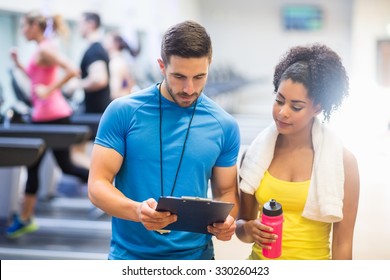Fit woman talking to her trainer at the gym