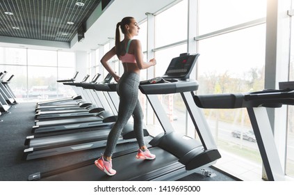 Fit woman training on treadmill near panoramic window in gym - Powered by Shutterstock