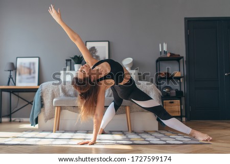 Fit woman trains at home, doing backbend.
