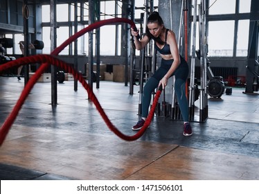 Fit woman using battle ropes during strength training at the gym. Athlete moving the ropes for burning fats at health club. - Shutterstock ID 1471506101