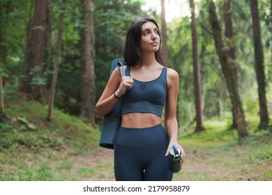 Fit Woman Walking In The Forest And Carrying A Yoga Mat