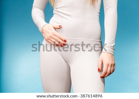Fit woman wearing hot gray sports thermolinen underwear, closeup part of body, studio shot on blue. Long sleeves top and leggings.