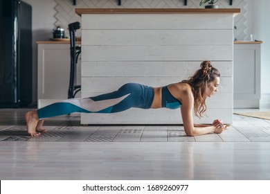 Fit woman working on abdominal muscles doing plank exercise, core workout at home.