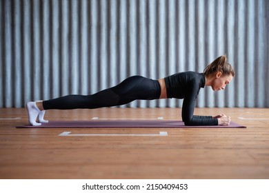 Fit woman working on abdominal muscles doing plank exercise, core workout.