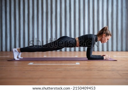 Fit woman working on abdominal muscles doing plank exercise, core workout.