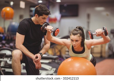 Fit woman working out with trainer at the gym