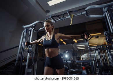 Fit woman workout at dark fitness center and using Cable crossover machine for exercise at her chest and arms. Healthy lifestyle Fitness and sport concept - Shutterstock ID 1995004565