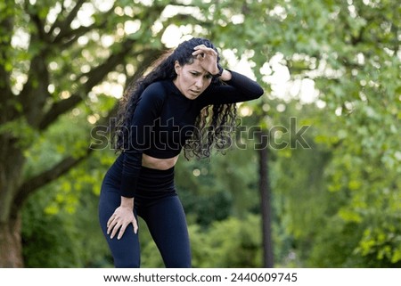 A fit woman in workout gear pauses for rest amidst greenery, capturing the essence of health and well-being.