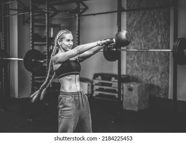 Fit woman works out with heavy kettlebell in modern gym. Functional muscle training. - Shutterstock ID 2184225453