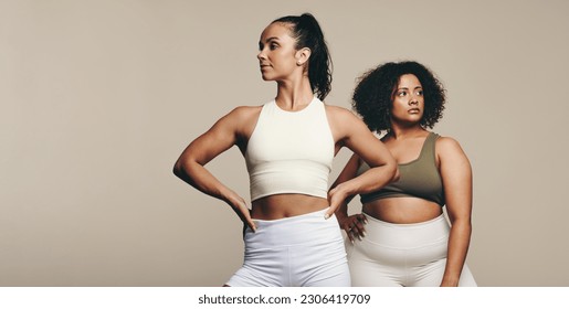 Fit women with diverse body shapes standing together in a studio, wearing sports clothing. Two female athletes showing off their bodies as they embrace a lifestyle of fitness and body training. - Powered by Shutterstock