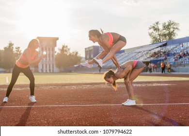 Fit women in the stadium playing leap frog.