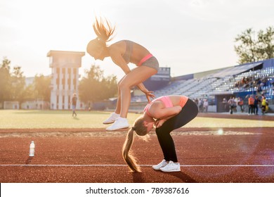 Fit women at the stadium playing leap frog.