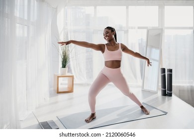 Fit young African American lady in sportswear practicing yoga, doing domestic fitness, foillowing online video at home gym, copy space. Pretty black woman enjoying domestic workout - Powered by Shutterstock