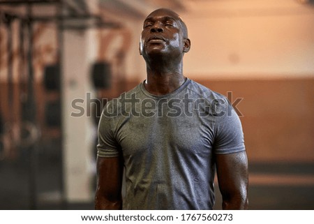 Fit young African American man standing with his eyes closed and sweating after a gym workout