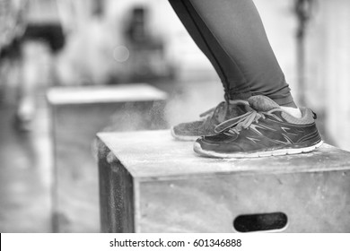 Fit young african american woman box jumping at a gym. Female athlete is performing box jumps at gym with focus on legs