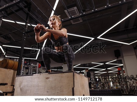 fit young ambitious blond woman doing a box jump exercise.hobby. side view full length photo. people concept