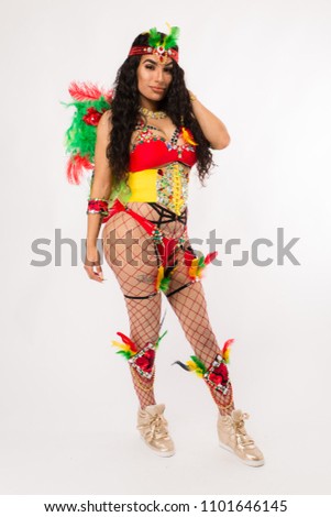 Fit young dark haired hispanic woman in Carnaval costume and athletic shoes posing on clean white background