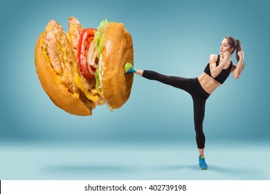 Fit, Young, Energetic Woman Boxing Hamburger As Unhealthy Food