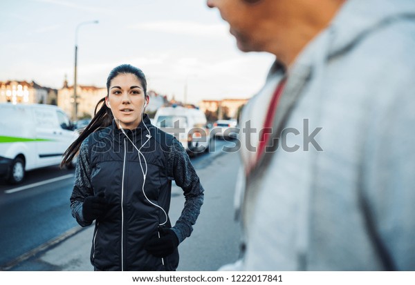 A fit young female runner running outdoors on the\
bridge in Prague city.