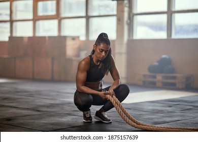 Fit young Indian woman in sportswear taking a break from a battle rope workout in a gym - Powered by Shutterstock