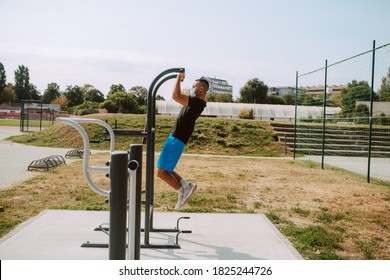 Fit Young Male Caucasian Athlete With Face Mask  Trains On Arm And Leg Equipment In An Outdoor Gym. Muscular Athlete Outdoors.  COVID - 19 Coronavirus Protection