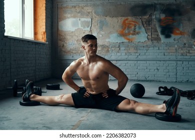 Fit Young Man Holding Hands On Hip While Doing The Splits In Gym