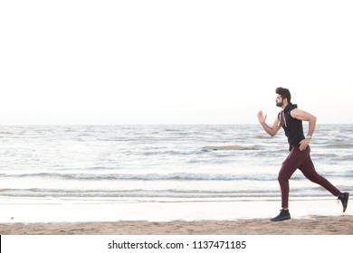 Fit Young Man Jogging Along The Beach