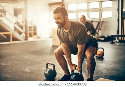 Fit young man looking focused while working out with dumbbells during an exercise class at a gym