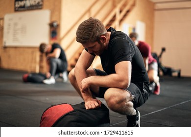 Fit young man in sportswear looking exhausted after an exercise class with weight bags at a gym - Shutterstock ID 1729411615