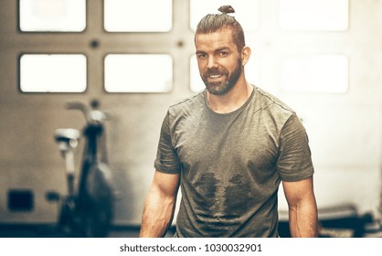 Fit Young Man In Sportswear Smiling While Standing Alone In A Gym Sweating After A Workout Session