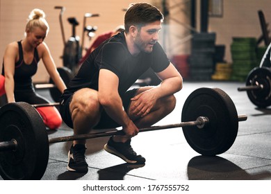 Fit young man in sportswear squatting in front of some heavy weights during a strength training class at the gym - Shutterstock ID 1767555752
