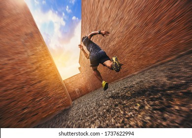 Fit young man at start running. Runner start a race on a rock track with tall red brick wall as background. Break through the dead end concept. Speed zoom blur