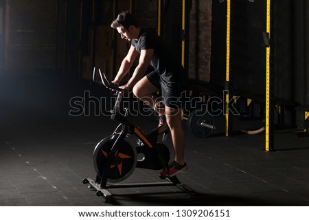 Fit young man using exercise bike at the gym. 