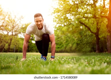 Fit young man and woman exercising in park. Smiling caucasian couple doing workouts on grass on sunny morning.