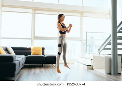 Fit young Pacific Islander woman training at home. Beautiful female athlete working out for wellbeing in domestic gym, training legs muscles with squats and jumps. - Powered by Shutterstock