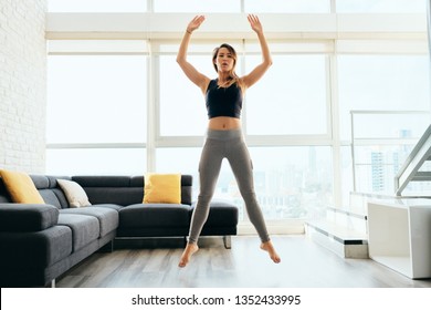 Fit Young Pacific Islander Woman Training At Home. Beautiful Female Athlete Working Out For Wellbeing In Domestic Gym, Training Legs Muscles With Squats And Jumps.