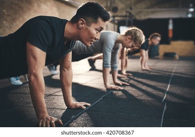 Fit young people doing pushups in a gym looking focused - Shutterstock ID 420708367