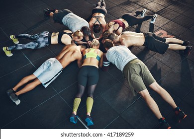 Fit young people focused on planking in a circle in a gym - Shutterstock ID 417189259