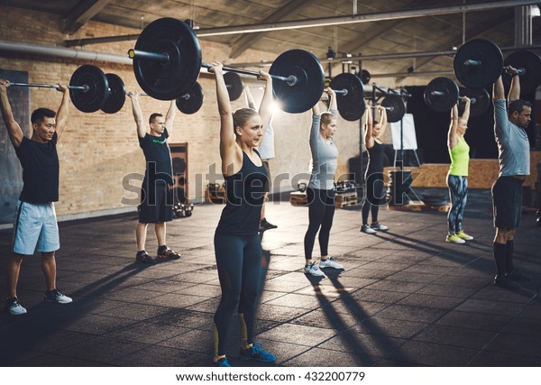 Fit young people lifting barbells looking focused,
working out in a gym 