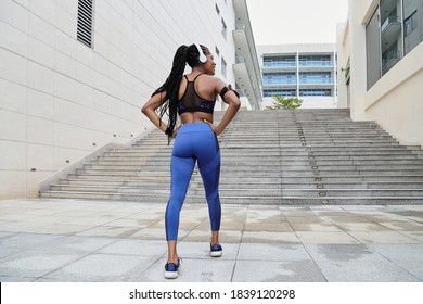 Fit young sportswoman standing in front of stairs with hands on her waist - Powered by Shutterstock