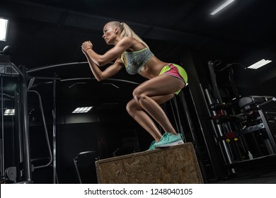 Fit young woman box jumping at a crossfit style. Female athlete is performing box jumps at gym