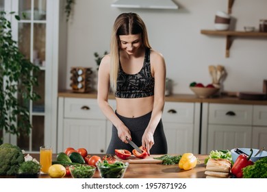 Fit Young Woman Cooking Fresh Salad At Home Standing In Kitchen Adding Exotic Spices To Mixture. Healthy Eating Concept.