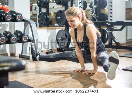 Fit young woman doing arms and legs balancing yoga training, handstand with legs apart in gym