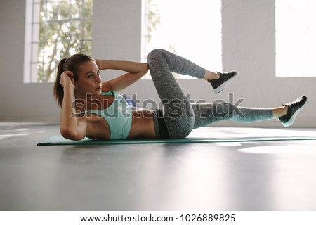 Fit young woman doing bicycle crunch workout to improve her abs. Female in the gym doing sit-up exercise.