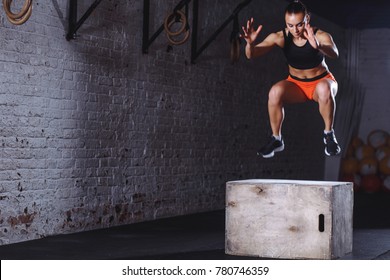 fit young woman doing box jump exercise. Muscular woman doing box jumps at gym