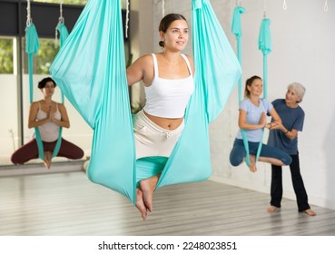 Fit young woman doing fly yoga stretching exercises in fitness training gym loft classroom. Sport healthy lifestyle concept - Powered by Shutterstock