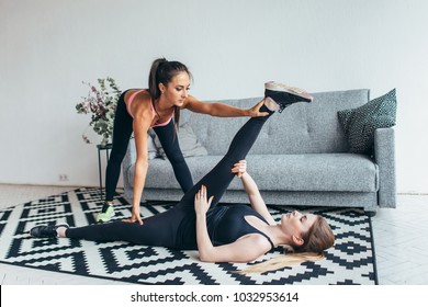 Fit Young Woman Doing Stretching Exercises With The Help Of Personal Trainer At Home