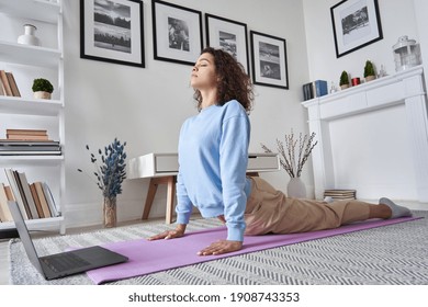 Fit young woman doing yoga exercise watching tv yoga class learning position with fitness tutorial on laptop computer stretching on mat at home, training body flexibility, online workout concept. - Powered by Shutterstock