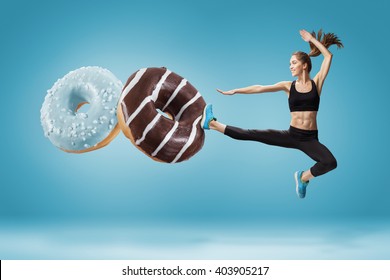 Fit Young Woman Fighting Off Bad Food On A Blue Background